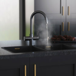 a swan neck gunmetal 4 in 1 kitchen tap dispensing hot water on a sink