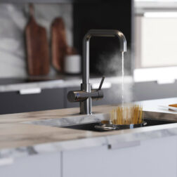 A gun metal d-neck tap in a modern kitchen dispensing boiling water into a pan of pasta