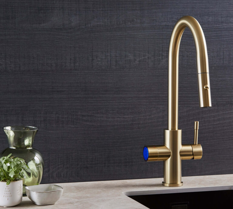 gold sparkling tap in modern kitchen with plant next to it